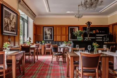 a restaurant with tables and chairs and a chandelier at Hotel Golfi in Poděbrady
