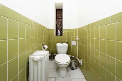 a bathroom with a white toilet and green tiles at Peter's Tower Apartments in Prague