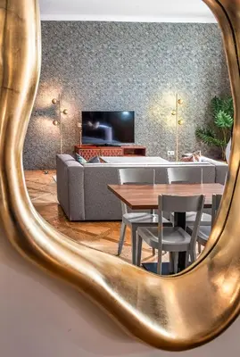 a mirror reflecting a living room with a couch and table at Golden Angel Suites by Adrez in Prague