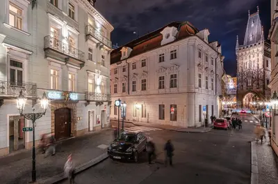 a group of people crossing a street in a city at night at Golden Angel Suites by Adrez in Prague