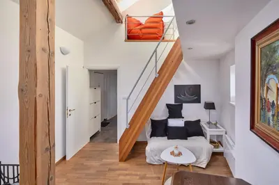 a white bedroom with a white bed with a green blanket at Prague Days - Loft with Relax Zone near Vltava River in New Town in Prague