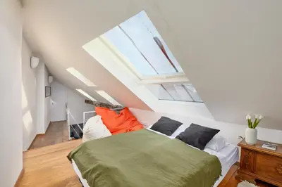 a attic bedroom with a bed and a skylight at Prague Days - Loft with Relax Zone near Vltava River in New Town in Prague