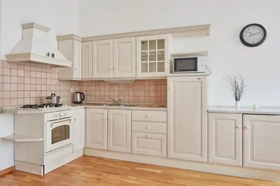 a kitchen with white cabinets and a clock on the wall at Prague Days - One-bedroom Apartment with Balcony and Elevated Chill Zone in Old Town in Prague