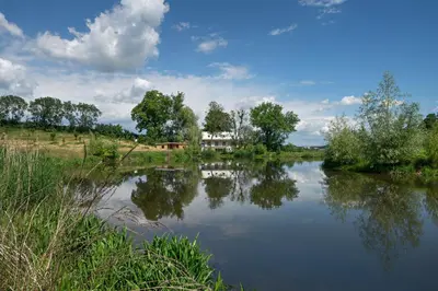 a view of a river with a house in the background at Smilovický Mlýn in Rakovník