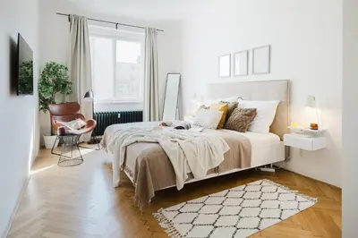 a white bedroom with a bed and a chair at Prague Days - One-bedroom Apartment with Netflix and Workspace with iMac in New Town in Prague