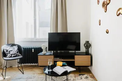 a living room with a tv and a table and a chair at Prague Days - One-bedroom Apartment with Netflix and Workspace with iMac in New Town in Prague
