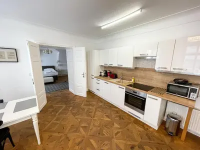 a kitchen with white cabinets and a table and a bed at U Obecního dvora - Old Town Apartment in Prague