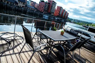 a table and chairs on a deck next to the water at Houseboat Bonanza Prague in Prague