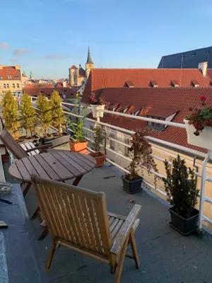 a balcony with a wooden bench and potted plants at Anenska by Charles Bridge 1 in Prague