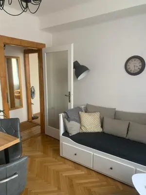 a living room with a couch and a clock on the wall at Anenska by Charles Bridge 1 in Prague