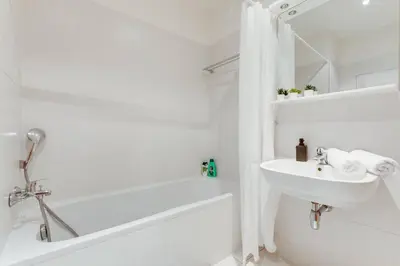 a white bathroom with a sink and a bath tub at JT's Apartments Korunní str. in Prague