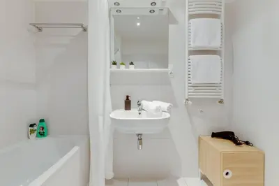 a white bathroom with a sink and a bath tub at JT's Apartments Korunní str. in Prague