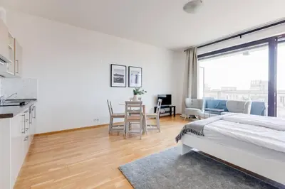a white bedroom with a bed and a dining room at JT's Apartments Korunní str. in Prague