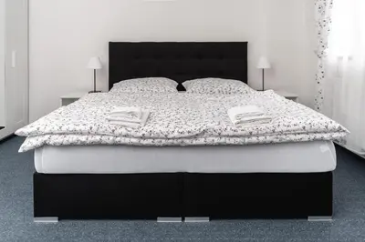 a bedroom with a black and white bed and two lamps at Penzion Grado Davle in Davle