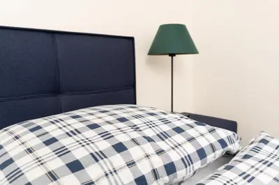 a bed with a blue and white pillow and a lamp at Penzion Grado Davle in Davle
