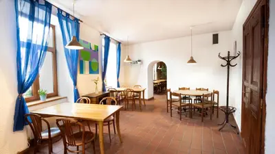 a dining room with tables and chairs and blue curtains at Penzion Grado Davle in Davle
