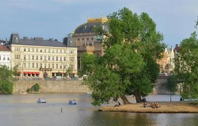 a tree on an island in the water near a building at Wishlist Prague Residences Malá Strana in Prague