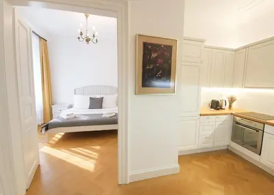 a kitchen with white cabinets and a bed in a room at Wishlist Prague Residences Malá Strana in Prague