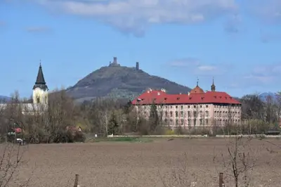 a large building with a mountain in the background at Rodinný dům pod Hazemburkem in Libochovice