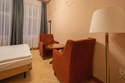 a hotel room with a bed and a chair and a lamp at 4 Bedrooms 130m2 apartment at the Main City Square in Prague