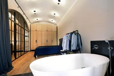 a bathroom with a large white tub and a bedroom at Design Loft 2 Minutes to Wenceslas square in Prague