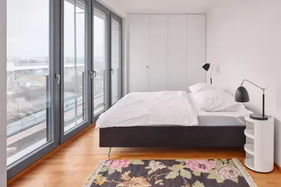 a white bedroom with a bed and a large window at Prague Days - Spacious Apartment with Balcony by the Vltava river in Karlin in Prague