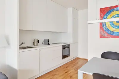 a kitchen with white cabinets and a table at Prague Days - Spacious Apartment with Balcony by the Vltava river in Karlin in Prague