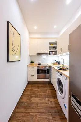 a kitchen with white cabinets and a washer and dryer at Prague Days - Practical and fully equipped studio near National Museum in Prague