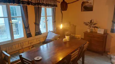 a dining room with a wooden table and windows at Hlučov Lesní Chalupa in Kokořín