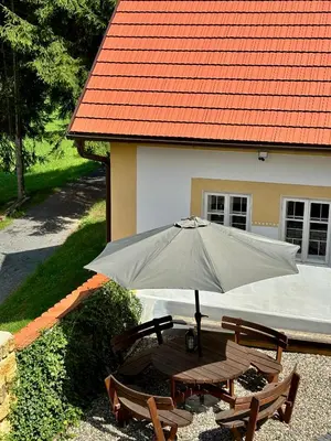 a table and chairs with an umbrella in front of a house at Hlučov Lesní Chalupa in Kokořín