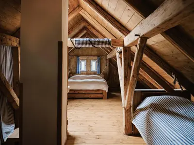 a bedroom with a bed in a wooden attic at Hlučov - Penzion & Restaurace in Kaninský Dŭl