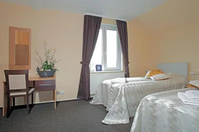 a bedroom with two beds and a desk and a window at Wine Pension Prague in Prague