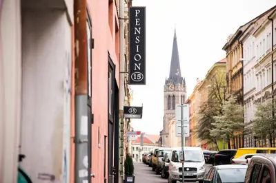 a street with cars parked on a city street with a church at Pension 15 Homér in Prague