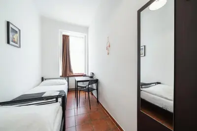 a room with two beds and a desk and a window at Pension 15 Homér in Prague