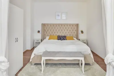 a white bedroom with a large bed with a large headboard at Nice and cozy apartment right at TV tower in Prague