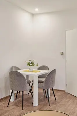 a white table with chairs and a white wall at Nice and cozy apartment right at TV tower in Prague
