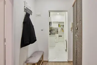 a small white hallway with a bench and a kitchen at Nice and cozy apartment right at TV tower in Prague