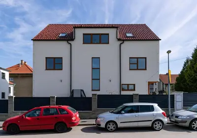 two cars parked in a parking lot in front of a house at Home Le Fame in Prague