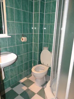 a green tiled bathroom with a toilet and a sink at Pension Europa in Prague