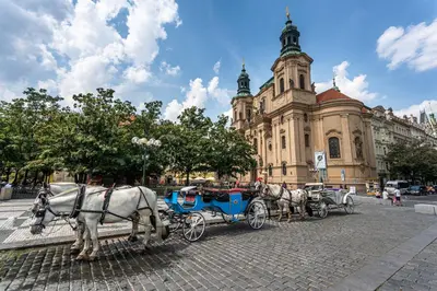 two white horses pulling a blue carriage in front of a building at Wishlist Old Prague Residences - Haštalská in Prague