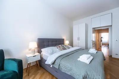 a bedroom with a large bed and a blue chair at Wishlist Old Prague Residences - Haštalská in Prague