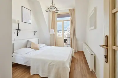 a white bedroom with a bed and a window at Prague Days - One-bedroom Apartment with View of Castle from Balcony near Wenceslas Square in Prague