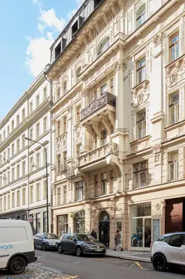 a large white building with cars parked in front of it at Prague Days - One-bedroom Apartment with View of Castle from Balcony near Wenceslas Square in Prague