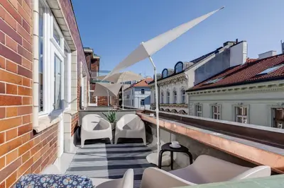 a balcony with chairs and an umbrella on a building at Riben House Prague in Prague