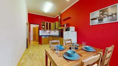 a dining room with a wooden table and a red wall at Apartmány Topolová 909B in Milovice