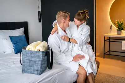a man and a woman sitting on a bed at Hotel & Spa Chariclea in Poděbrady