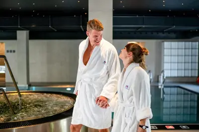 a man and woman in white robes standing next to a pool at Hotel & Spa Chariclea in Poděbrady