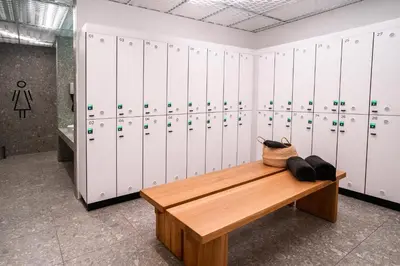 a locker room with white lockers and a wooden bench at Hotel & Spa Chariclea in Poděbrady