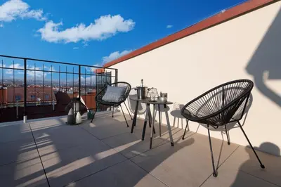 a patio with two chairs and a table on a roof at Hidden Art Boutique Residence by Dwellfort in Prague