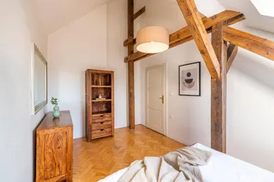 a bedroom with a bed and wooden beams at Štupartská - Tyn Church View Residence with terrace in Prague